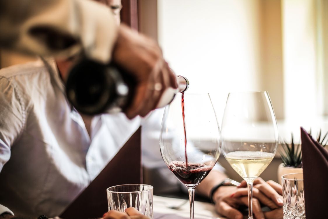 Rotwein wird in ein Glas eingeschenkt beim romantischen Abendessen