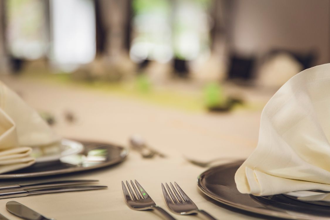 Fein eingedeckter Restauranttisch mit gefalteten Servietten und poliertem Besteck
