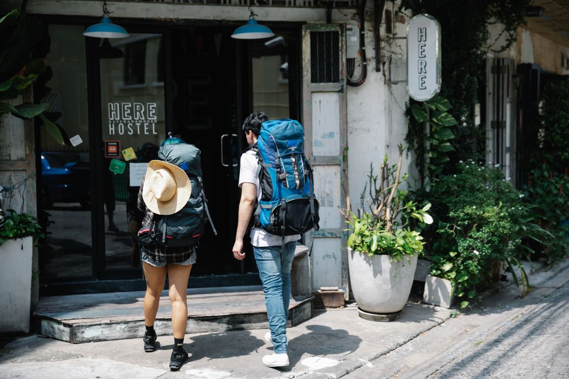 Paar mit Reisegepäck betritt ein Boutique-Hotel