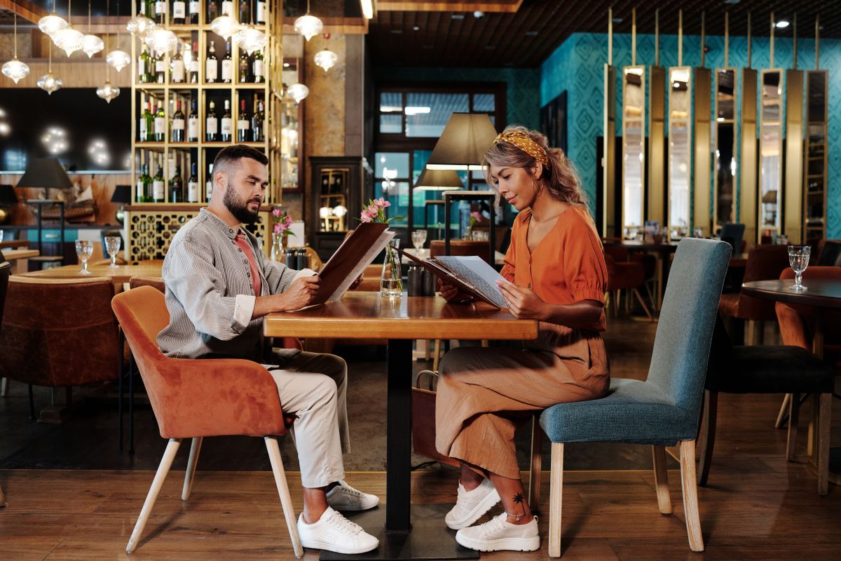 Elegantes Paar studiert gemeinsam die Speisekarte bei einem ersten Date im stilvollen Restaurant